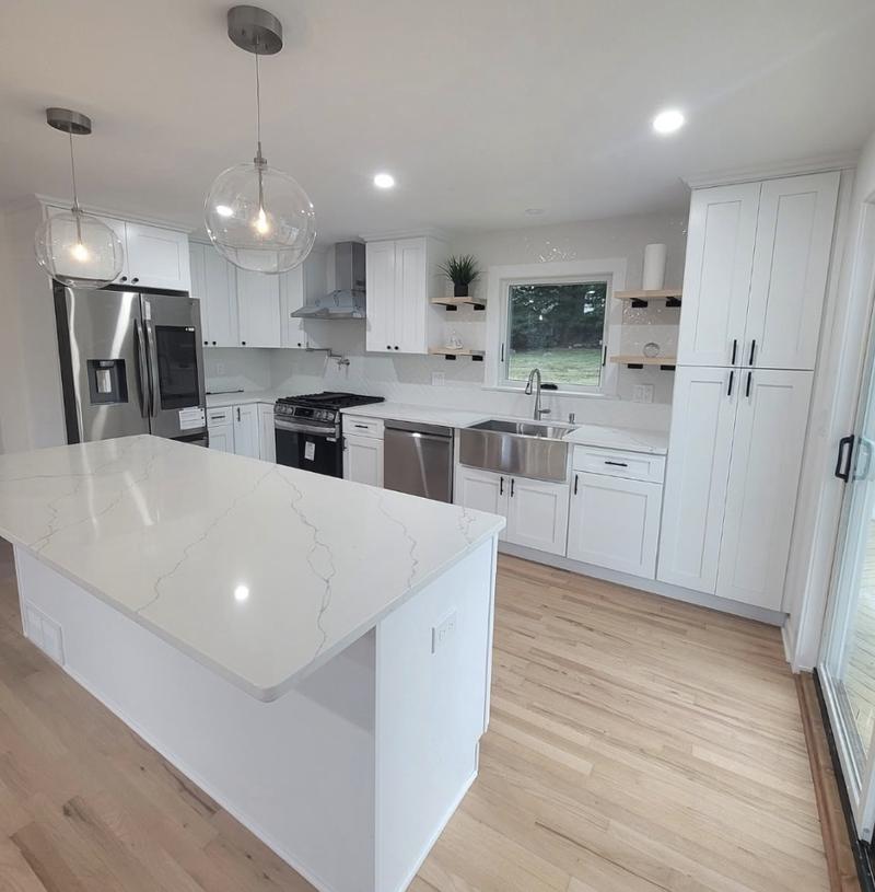 Kitchen remodel with white shaker cabinets, waterfall quartz island, glass globe pendants and a stainless apron sink by KJ Commercial in Hudson County NJ