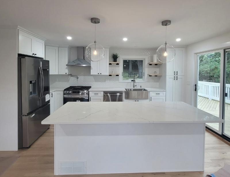 Kitchen remodel with a waterfall quartz island, glass globe pendants, gas range and stainless appliances by KJ Commercial in NJ