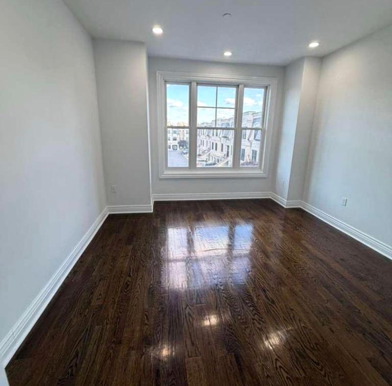 Freshly painted bedroom with clean ceiling cut lines and white window casing and baseboard by KJ Commercial in Hudson County NJ